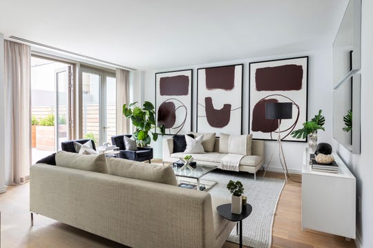 Three identical pieces of art are hung in a series in addition to two identical mirrors hung above a sideboard.