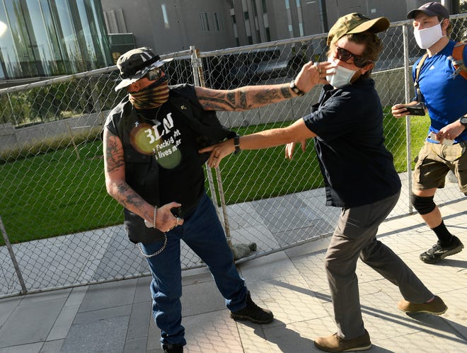 A man punches another man in Denver, Colo., Saturday, Oct. 10, 2020. The man on the left side of the photo was supporting the "Patriot Rally." He engaged with the man on the right, hit him in the face and sprayed him with Mace. The man at the right then shot and killed the protester at the left. At the time, two rallies were taking place near one another. Denver Channel 9News has confirmed that the man who did the shooting was a private security guard contracted by them and is in custody after the shooting.