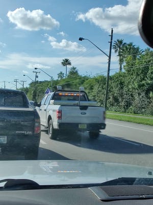 A Palm Beach County truck with a Trump flag affixed to the driver side window drives on Northlake Boulevard on Thursday.