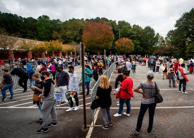 Hundreds of people wait in line for early voting on Monday, Oct. 12, 2020, in Marietta, Ga.  Eager voters have waited six hours or more in the former Republican stronghold of Cobb County, and lines have wrapped around buildings in solidly Democratic DeKalb County.