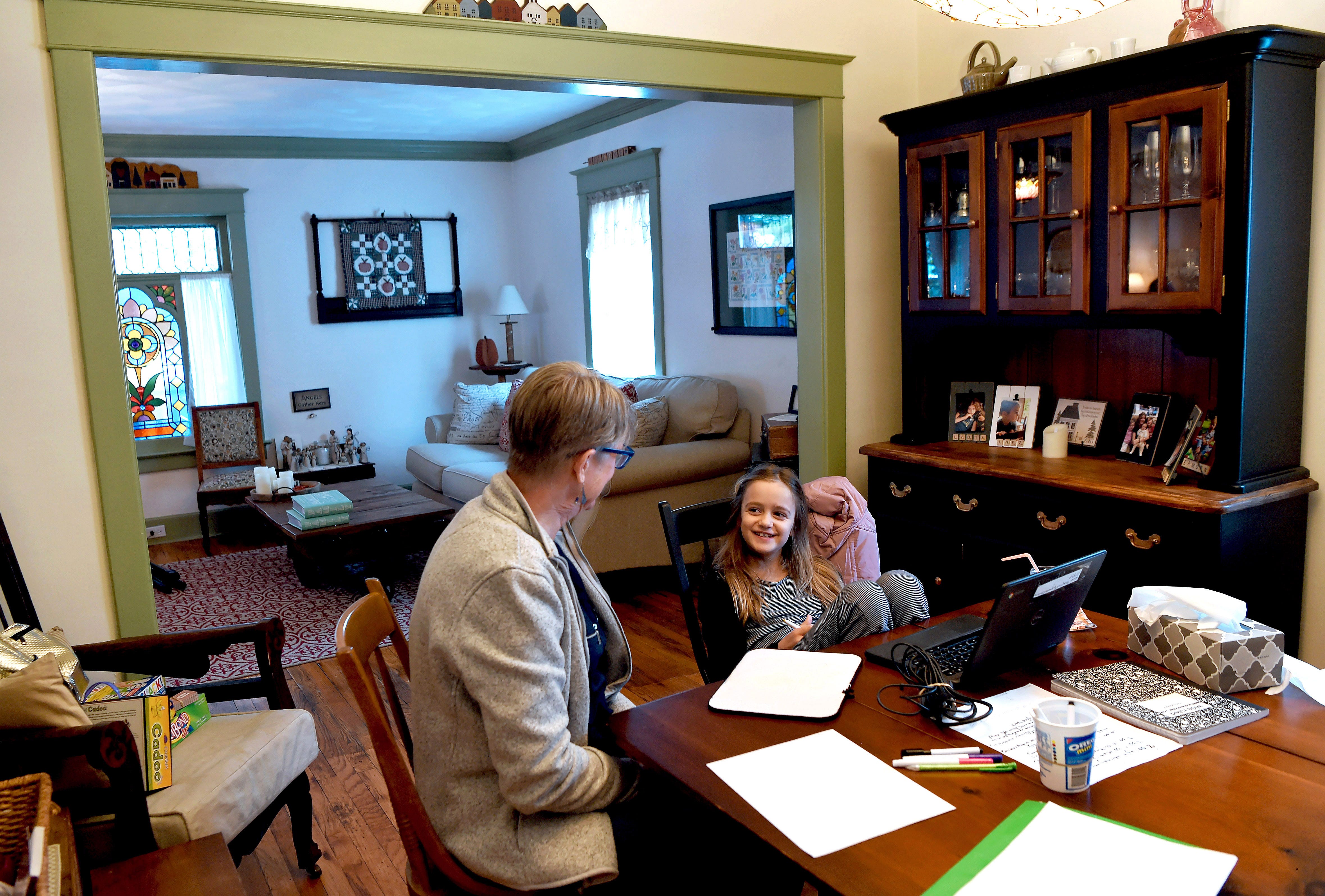 Renee Thompson and her granddaughter Norah Thompson share a laugh during the school day in Thompson's home in Binghamton, New York. Norah and her sister, Lydia, are students are on a hybrid schedule, attending classes in school two days a week and staying at their grandparents' home the other three while their parents, both teachers, are working.