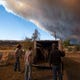 People stand near a stock trailer after loading livestock as smoke from the Cameron Peak Fire fills the sky in Masonville, Colo. on Wednesday, Oct. 14, 2020.
