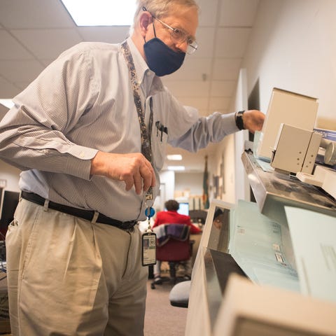 Deputy County Director Howard Sholl feeds mail-in 