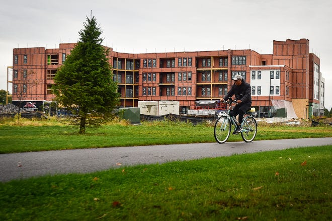 A man rides a bicycle along a trail near the construction site of Air City Lofts on Friday, Oct. 16, 2020 at Griffiss Business and Technology Park in Rome.