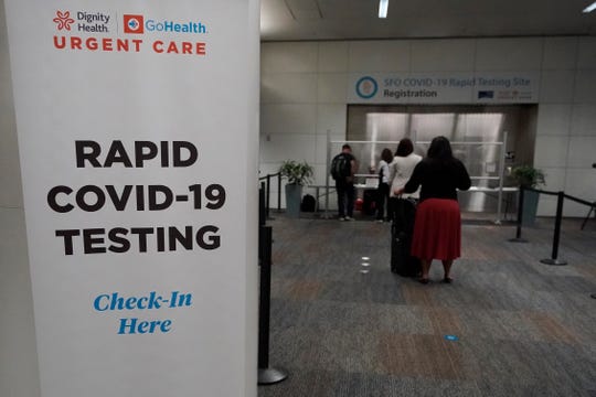 People wait in line to register for rapid COVID-19 testing at San Francisco International Airport on Thursday.