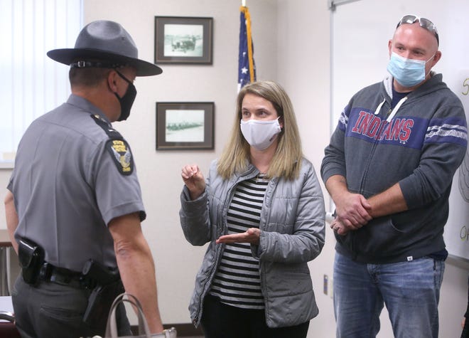 Christina Cudlip, of Wooster, speaks with Staff Lt. Bill Haymaker before receiving the "Saved by the Belt" award at the Ohio State Highway Patrol post in Jackson Township on Tuesday. Also visible in the background is Christina's husband, Matthew Cudlip.