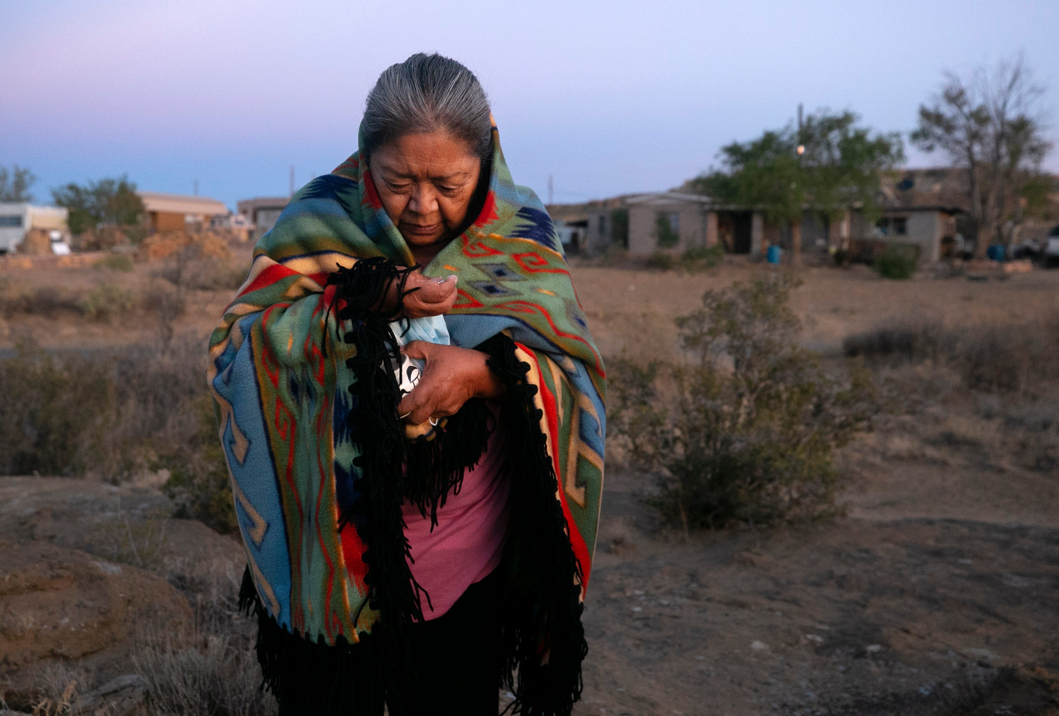 Beatrice Norton prays at sunrise while taking ground white corn in her hand in front of her home in Oraibi on the Hopi Reservation on Sept. 12, 2020.