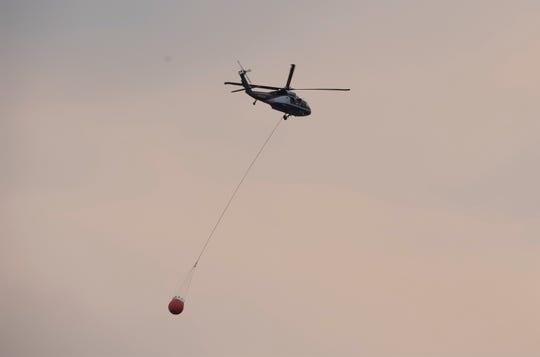 A helicopter carries water to fight the Cameron Peak Fire in Fort Collins, Colo. on Tuesday, Oct. 20, 2020.