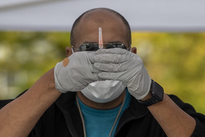 Brandon Beyor, an employee with Lower Lights Christian Health Center, prepares a flu shot at the free, drive-up flu vaccination tent outside the Broad Street Food Pantry in Columbus. Health officials warn that avoiding the flu is especially important this year, amid the COVID-19 pandemic.