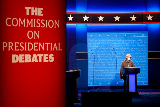 A member of the production crew stands at a podium near glass barriers to prevent the spread of COVID-19 on stage ahead of the final presidential debate between Republican candidate President Donald Trump and Democratic candidate former Vice President Joe Biden, Wednesday, Oct. 21, 2020, in Nashville, Tenn. The debate will take place Thursday, Oct. 22 at the Curb Event Center at Belmont University. (AP Photo/Julio Cortez)