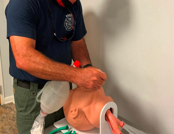 Firefighter Tony Pellegrin practices first aid while wearing a face mask. The coronavirus pandemic has caused fire departments to alter their procedures to help keep firefighters safe from infection.