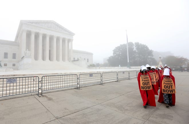 Protesters with the "Handmaids Brigade" march Oct. 22, 2020, outside the U.S. Supreme Court prior to a Senate Judiciary Committee hearing to vote on the nomination of Judge Amy Coney Barrett to the high court.