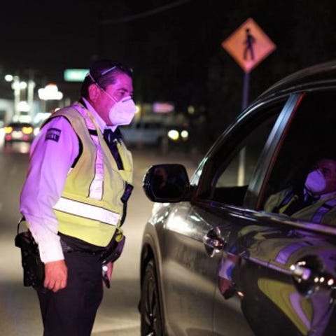 A Juárez traffic officer inspects a vehicle. A nig
