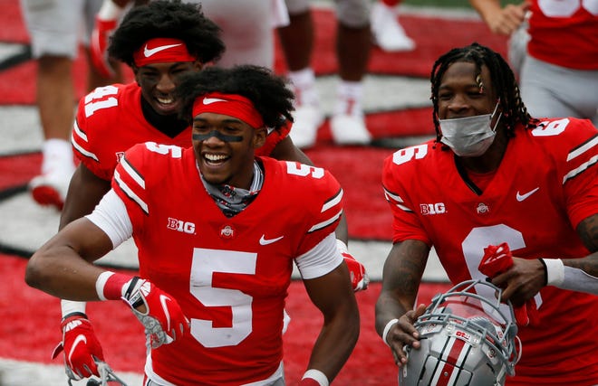 Ohio State Buckeyes wide receiver Garrett Wilson (5) smiles as he heads to the locker room with safety Josh Proctor (41) and wide receiver Jameson Williams (6) following the Buckeyes' 52-17 win over Nebraska last Saturday