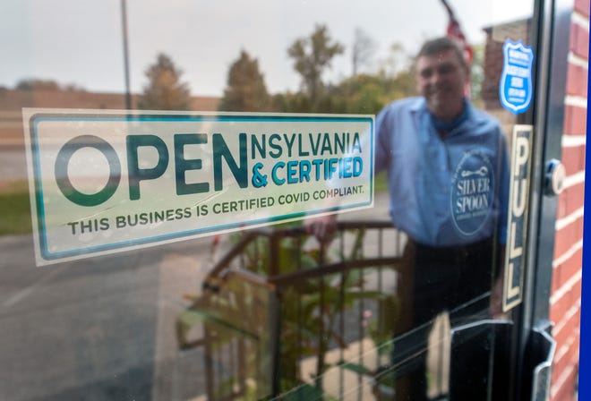 David LeHeron, the owner of the Blue Heron, reflects in the window displaying his Cerified Covid Compliant sign on the main entrance of the Springettsbury Township restaurant. The hospitality industry around central Pennsylvania, the rest of the state and country have struggled during the pandemic.