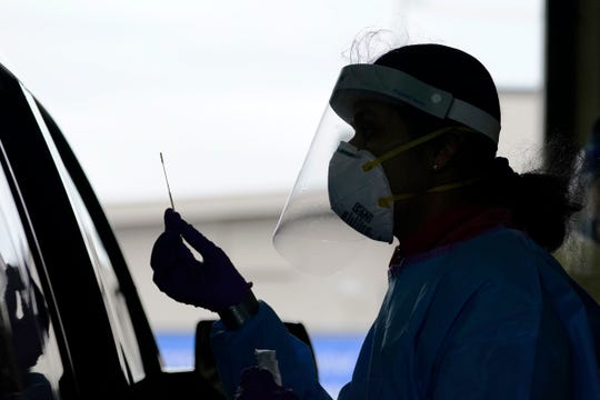 University of Washington research coordinator Rhoshni Prabhu holds up a swab after testing a passenger at a free COVID-19 testing site in Seattle on Oct. 23.