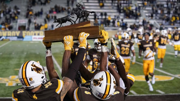 The Wyoming Cowboys celebrate with the Paniolo Tro