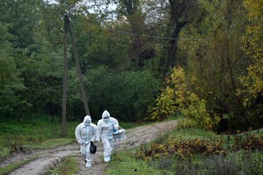 Members of a local electoral commission wearing personal protective equipment (PPE) walk with a mobile ballot box to visit villagers at their houses during Moldova's presidential election in the village of Stetcani, some 40 km north of Chisinau, on Nov. 1, 2020, amid the ongoing coronavirus disease pandemic.