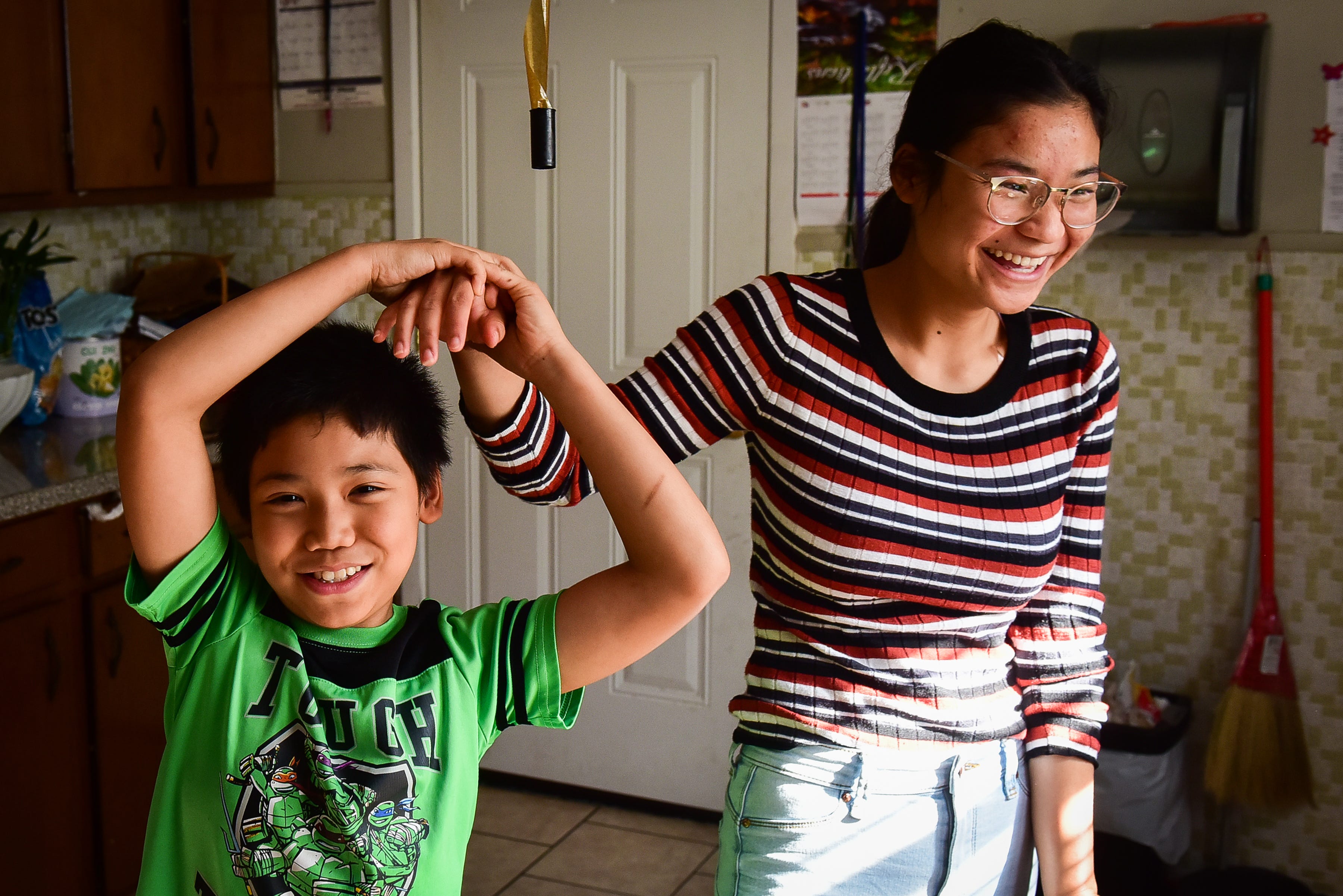 From left, Saw Kler Kaw Htoo plays with his older sister Kler Moo Paw as their family prepares dinner in the kitchen on Sunday, Oct. 25, 2020 at their home on Utica.