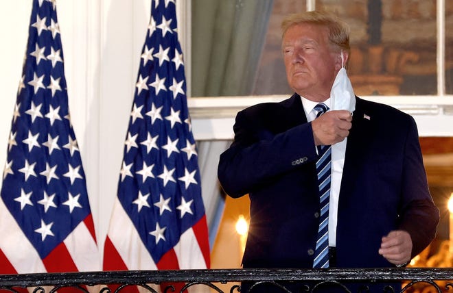 U.S. President Donald Trump removes his mask upon return to the White House from Walter Reed National Military Medical Center on Oct. 5. Trump spent three days hospitalized for coronavirus. (Win McNamee/Getty Images/TNS)