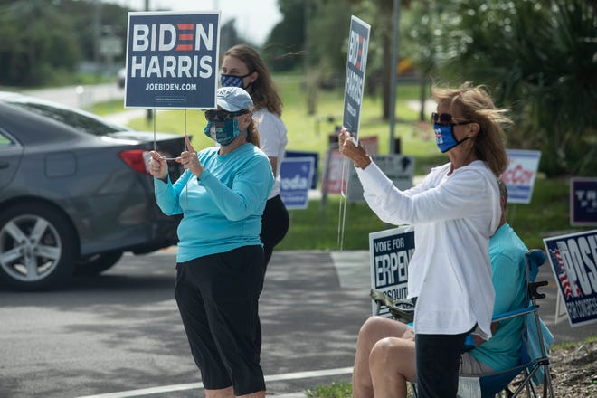 Marjie Flanigan (center), and Mary Lahey (right), both of Vero Beach, hold up signs with other Biden supporters in front of the Gifford Community Center on Election Day, Tuesday, Nov. 3, 2020, in Indian River County. 