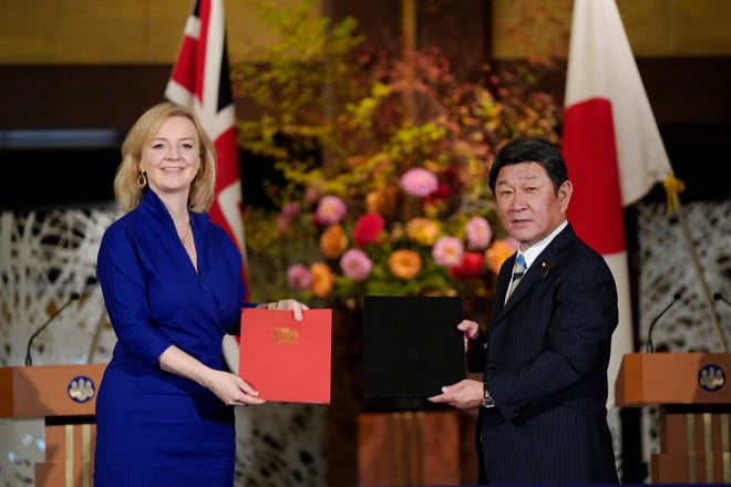 British International Trade Secretary Liz Truss, left, and Japanese Foreign Minister Toshimitsu Motegi exchange agreement documents for economic partnership between Japan and Britain at Iikura Annex of the Foreign Ministry in Tokyo, Friday, Oct. 23, 2020.