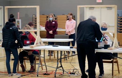 Poll observers Kelly Swartz, left, and Kathy Thulien watch as citizens receive their ballots to vote at Faith Lutheran Church Celebration Ministry Center on November 3, 2020, in Appleton, Wis.