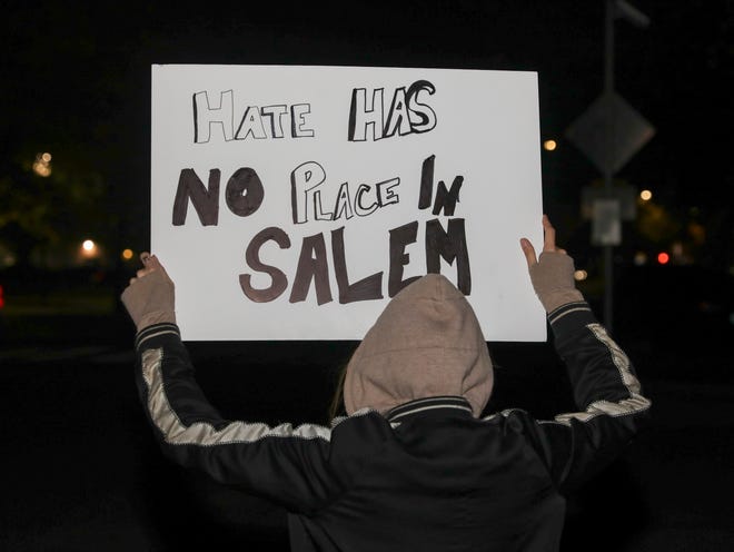 A person holds a sign as cars pass at a Demand Democracy gathering at the Oregon State Capitol in Salem, Oregon on Wednesday, Nov. 4, 2020. 