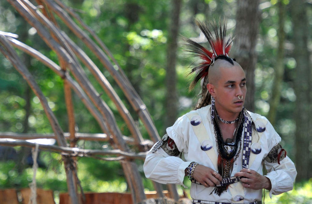 Phillip Wynne adjusts his outfit next to a wetu before the grand entry at the annual Mashpee Wampanoag Powwow in 2011.