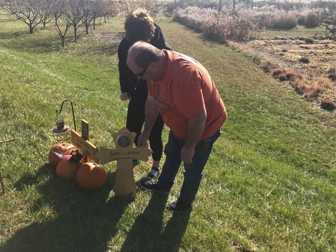 Leslie and Terry Robbins place a cross at a makeshift memorial where their son, Justin Wilson, was stuck and killed by a driver on Sagamore Parkway north of Brady Lane.