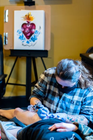 Cloak and Candle artist Princess tattoos a phoenix on a client. Custom pieces of art can also be created, like the heart seen in the background.