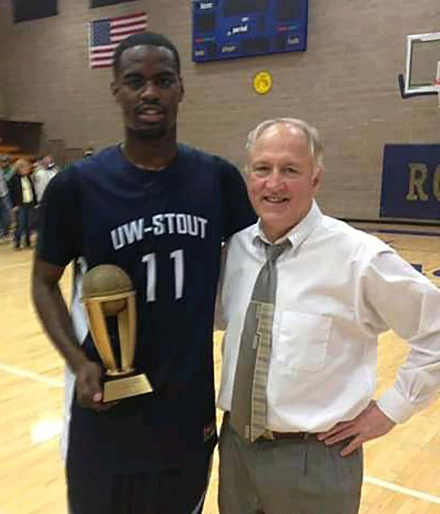 Jarvis Ragland with his coach Eddie Andrist at the University of Wisconsin-Stout. Ragland holds a trophy for MVP during a basketball tournament while on the team at the university.