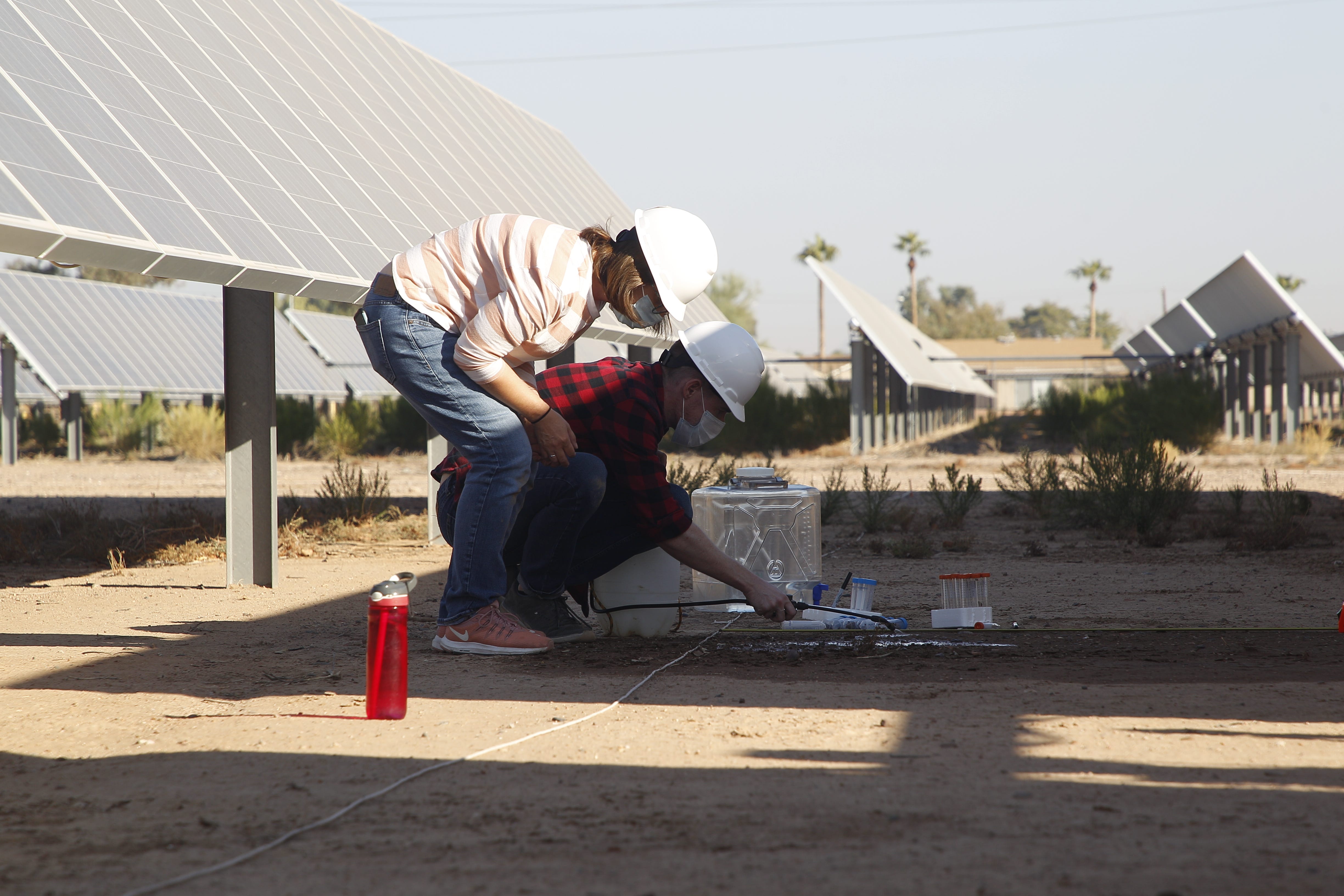 ASU research assistants Corey Nelson and Julie Rakes spray soil with water to see where biocrust grows.