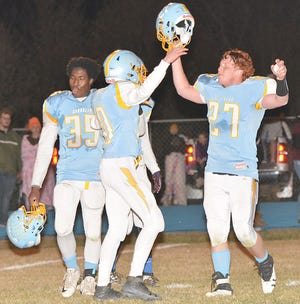 Hamlin players Sam Grantham (35) and cousins Tyson Stevenson (10) and Michael Stevenson (27) celebrate after the Chargers’ 28-6 victory over Lemmon-McIntosh in the 9AA semifinals.