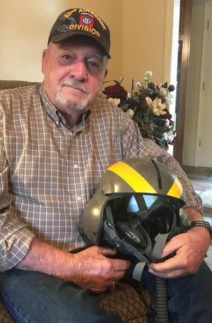 Bob Dickens holds one of the helmets he wore as a pilot of an attack helicopter in Vietnam.