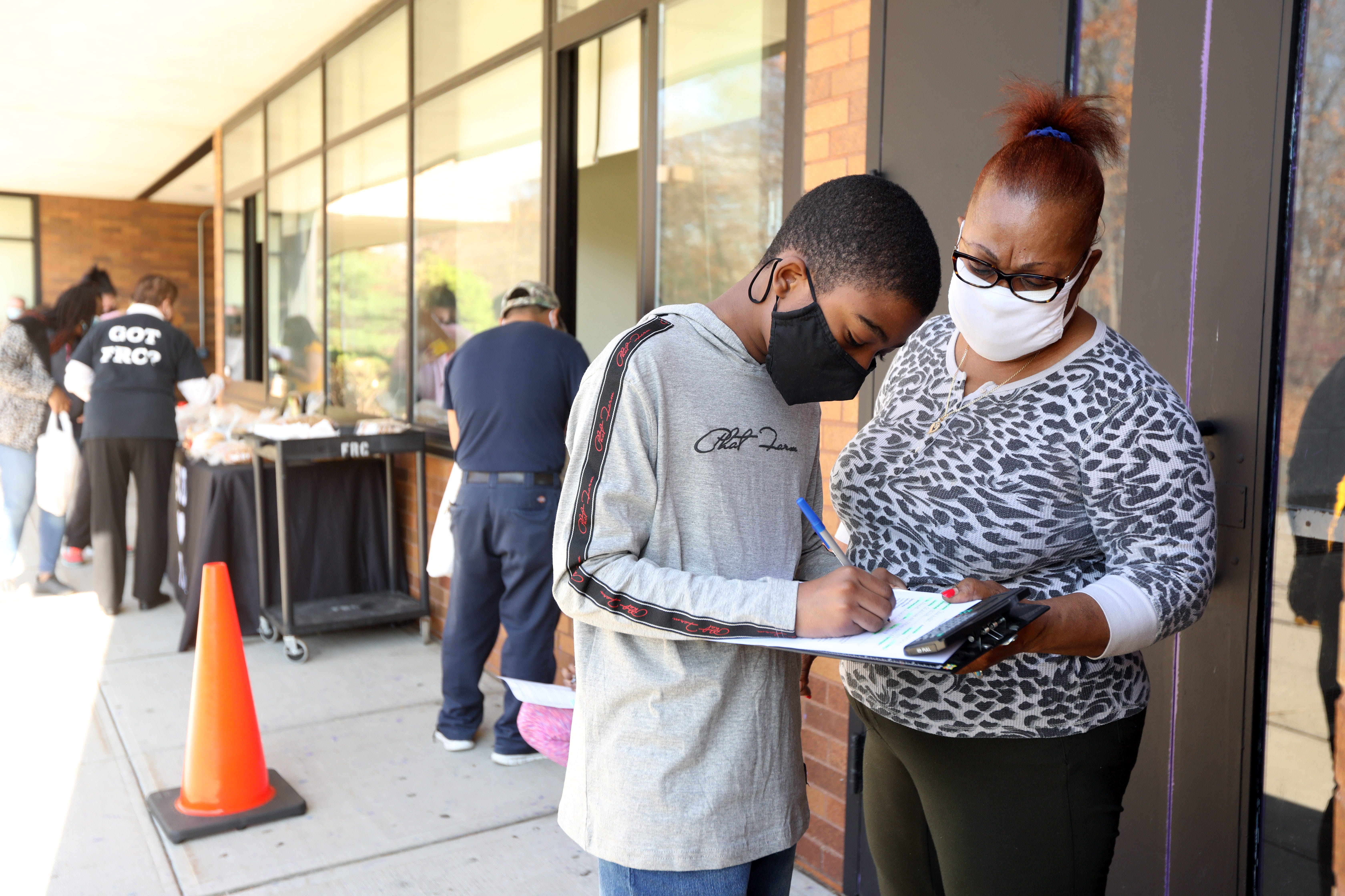 Seventh-grader Lensky Jean-Pierre, 12, and his mother, Gisele, fill out paperwork to receive a Chromebook on Nov. 10 at Chestnut Ridge Middle School in New York. Jean-Pierre had been using his mother's phone for his school work and hoped the Chromebook would make it easier to do his work.