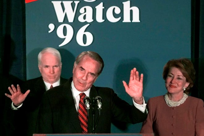 In this Nov. 5, 1996, file photo, Republican presidential candidate Bob Dole waves to supporters during his concession speech to supporters at a Washington hotel, with Sen. John McCain, R-Ariz., left, and wife Elizabeth, right. President Bill Clinton won re-election in a coast-to-coast landslide.