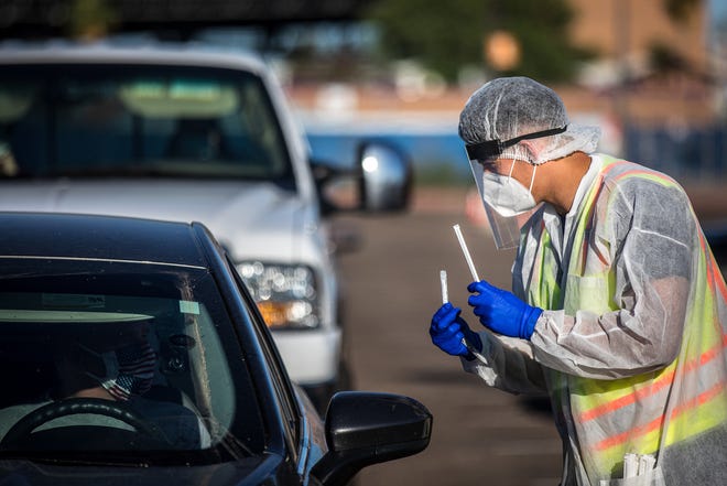 Medical volunteers give instructions on using the straws and vials for collection at a free saliva-based testing event on July 18, 2020, at Ak-Chin Pavilion in west Phoenix.