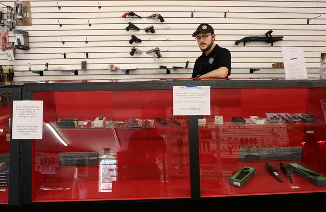 Metal Gear Armory manager Tyler Hendricks shows the empty wall racks and shelving that used to be fully stocked with ammo and guns at his store in Lancaster on Friday.
