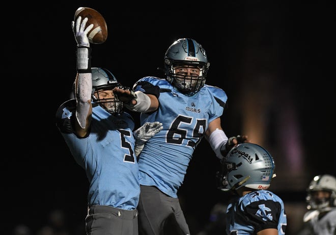 Alex Watters (5) and Bo Poljan of Lansing Catholic celebrate a Cougar touchdown against Olivet Friday, Nov. 13, 2020, during the district final at Lansing Catholic.