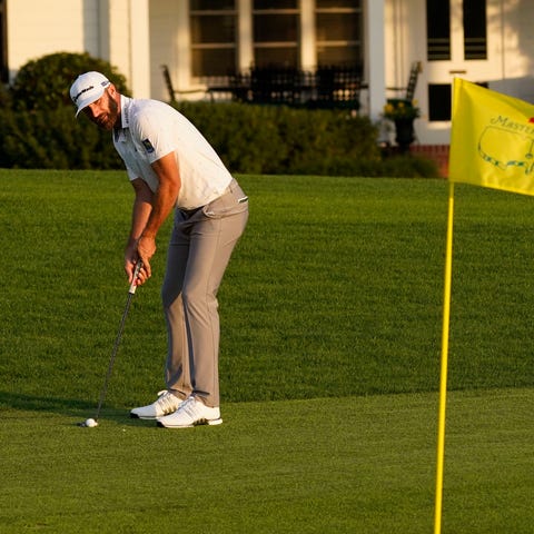 Dustin Johnson putts on the 18th green in front of