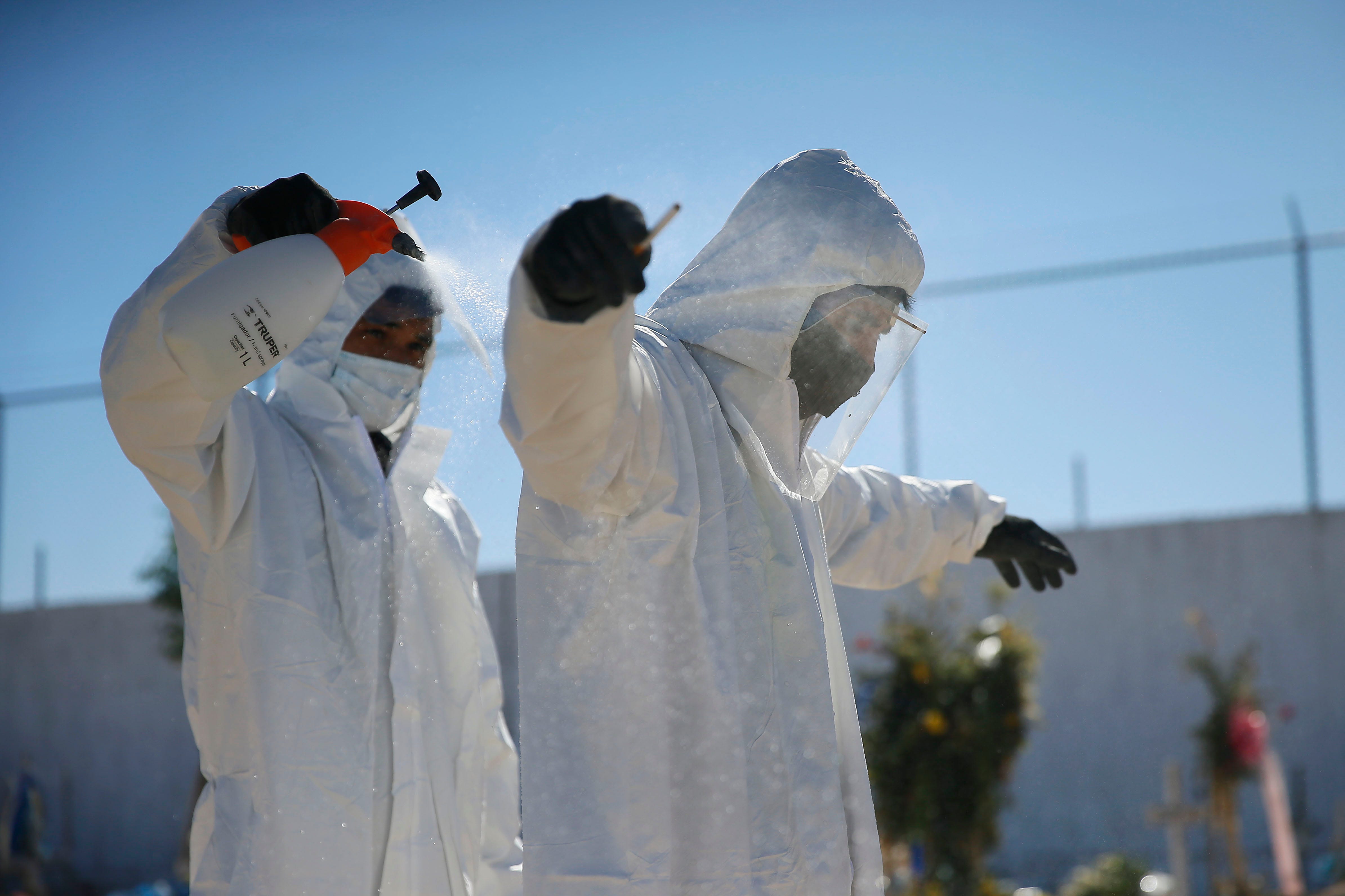 Workers at Parque Funeral Sueños Eternos spray each other with a water and bleach mixture after burying a COVID-19 victim.