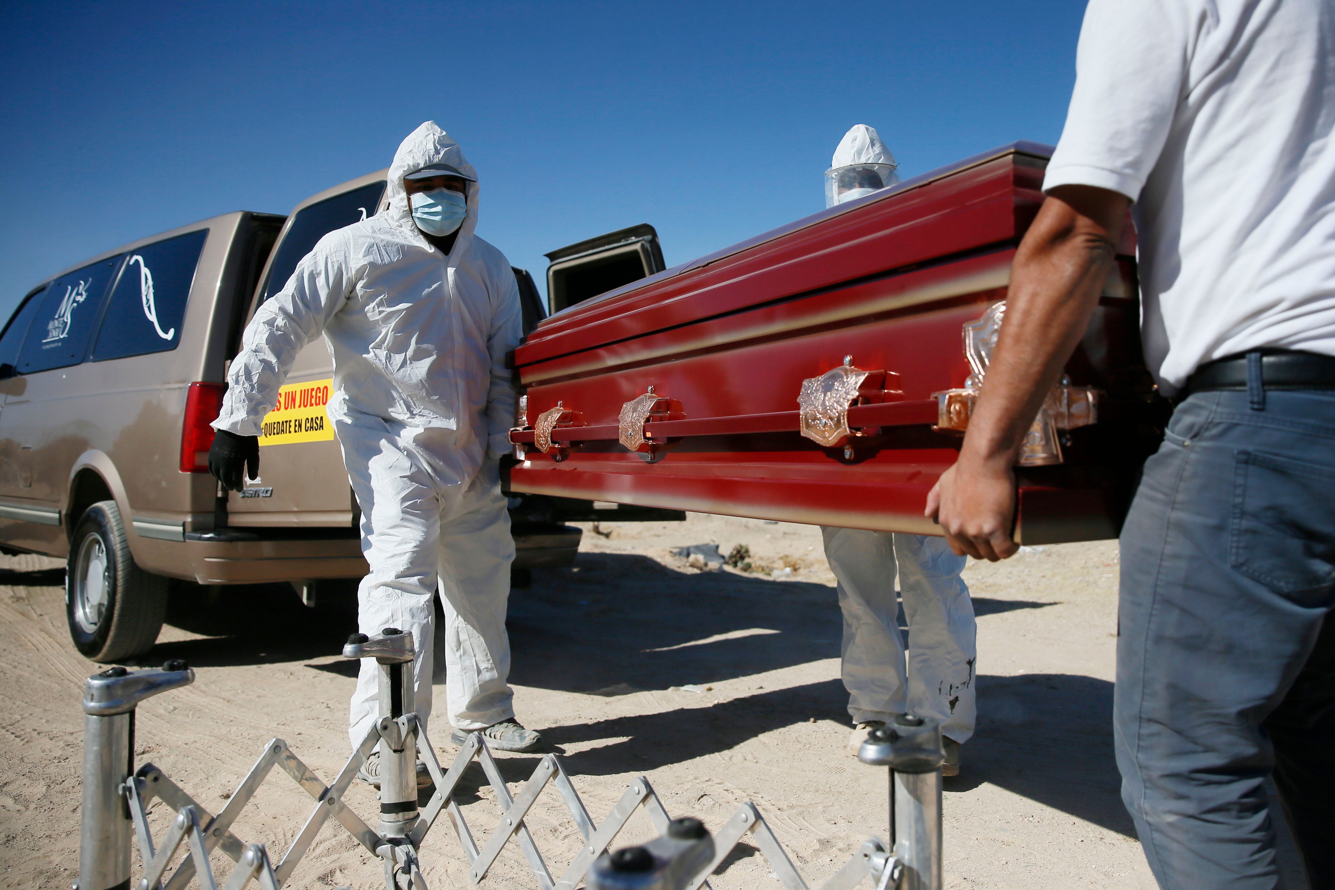 Gravediggers bury a coronavirus victim in Ciudad Juárez, Mexico. The sign on the van door reads, "this isn't a game stay at home."