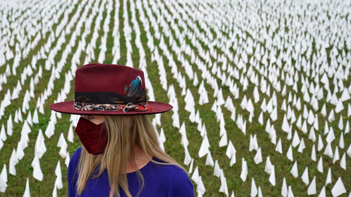 Artist Suzanne Brennan Firstenberg stands among thousands of white flags planted in remembrance of Americans who have died of COVID-19, on Oct. 27, 2020, near Robert F. Kennedy Memorial Stadium in Washington.