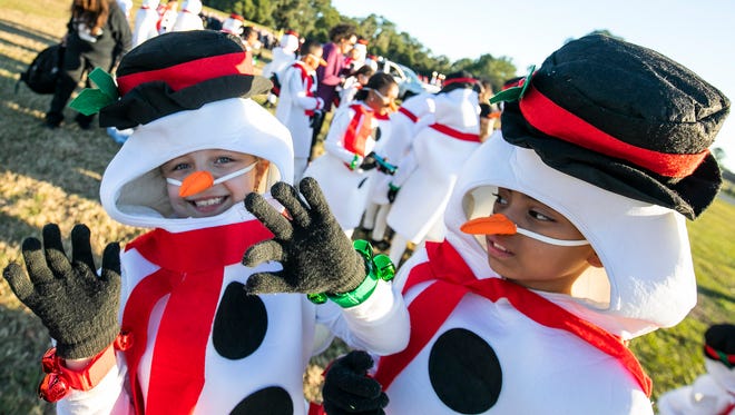 Members of the Sunrise Elementary School Dance Team, Rylen Tidwell, 9, left, was getting into the holiday spirit while dancing in her snowman outfit as fellow snowman Alissa Lobato, 9, right, watched.  The group was preparing to march in the annual Ocala/Marion County Christmas Parade.  Different community organizations staged their floats at the McPherson Government Complex Saturday December 14, 2019 to follow the parade route from SE 25th Avenue to NE 8th Avenue. [Doug Engle/Ocala Star-Banner]2019