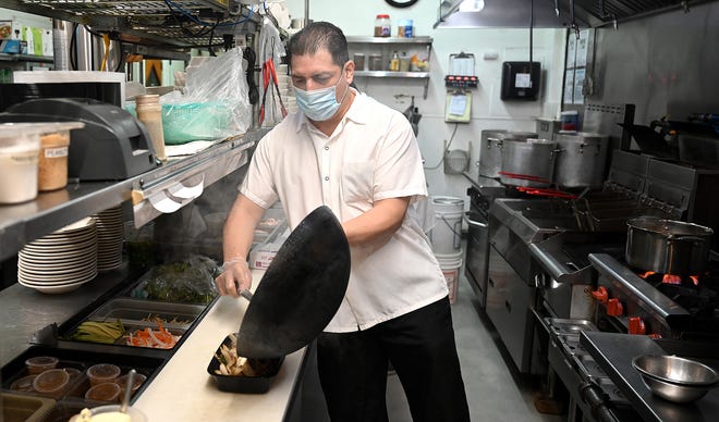 Chef Jose Mancia prepares a sizzling Mongolian beef dish at Pho Dakao in Framingham. Owner Dang Pham said the restaurant recycles, but there's room for improvement.