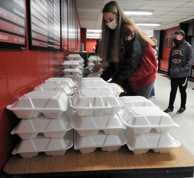 Student volunteers put to-go boxes in bags for running out to cars during the 17th annual community Thanksgiving dinner Wednesday at Coshocton High School. it was done drive-thru style due to the COVID-19 pandemic.