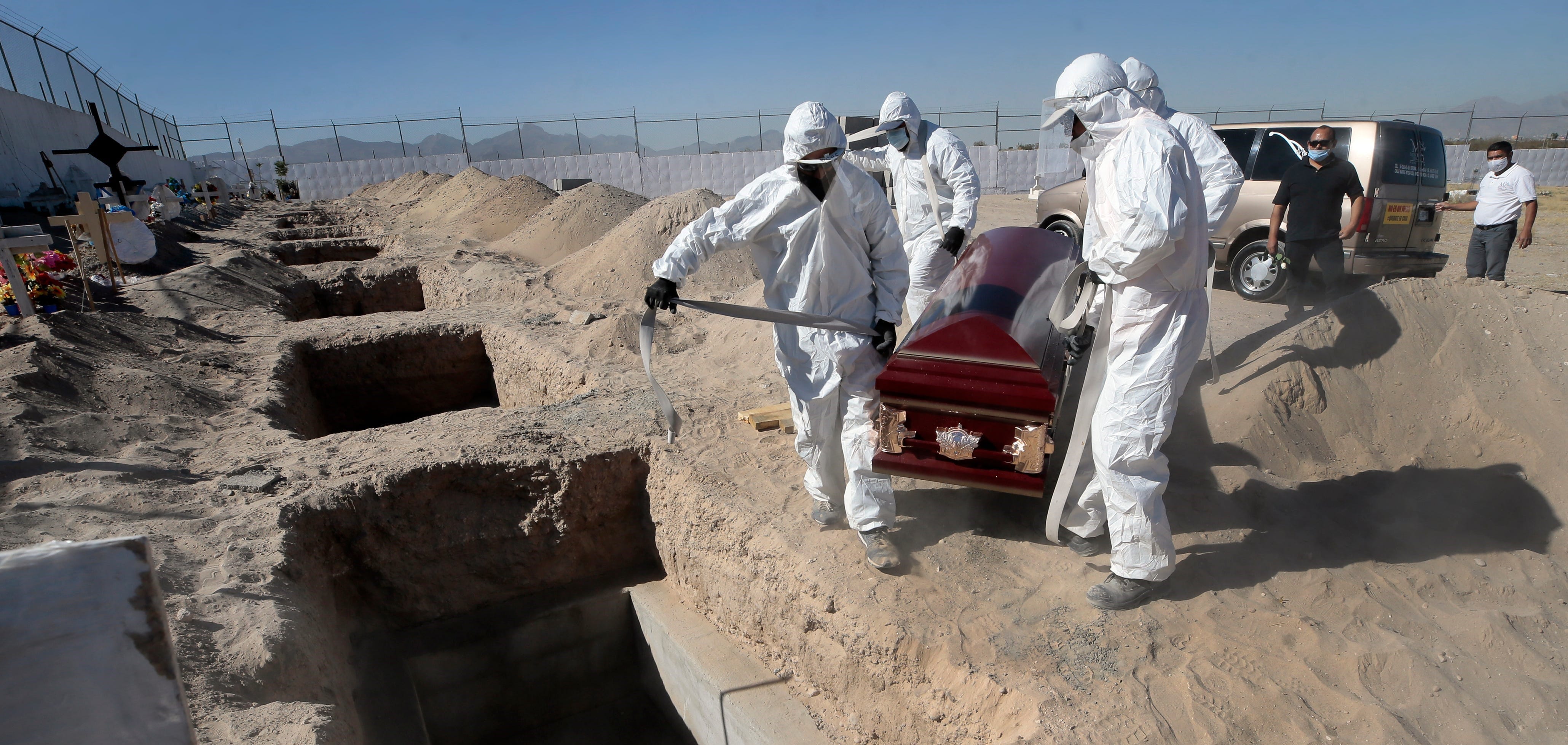 Cemetery workers carry a casket to a specially prepared COVID-19 grave as coronavirus deaths continue to rise in Juarez, Mexico.