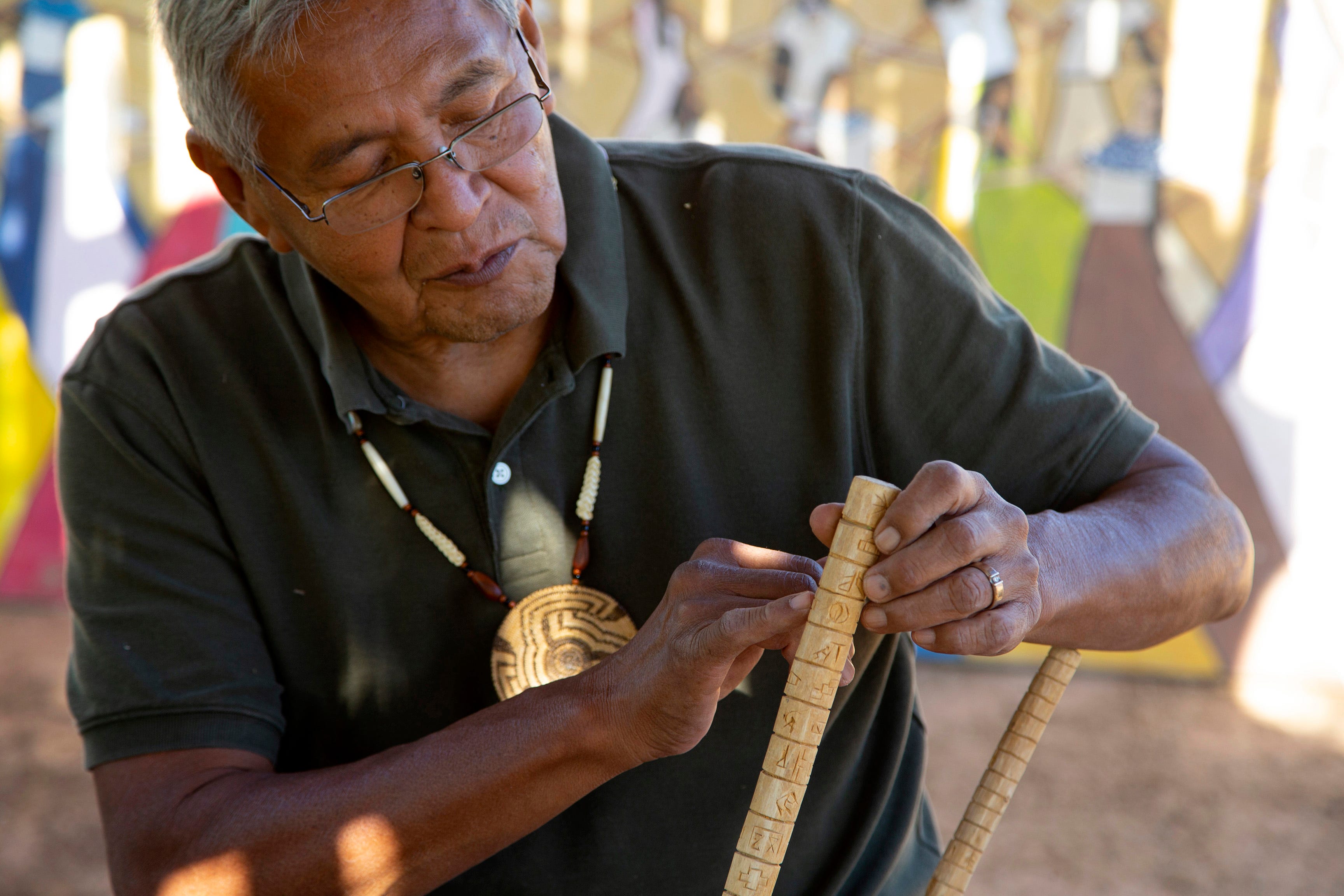 Royce Manuel, Salt River Pima-Maricopa Indian Community elder, uses traditional materials create bow, arrows, baskets, and flutes. Manuel reads a calendar stick he created. Tribal artisans, cultural practitioners are experiencing issues in finding the natural materials they need.