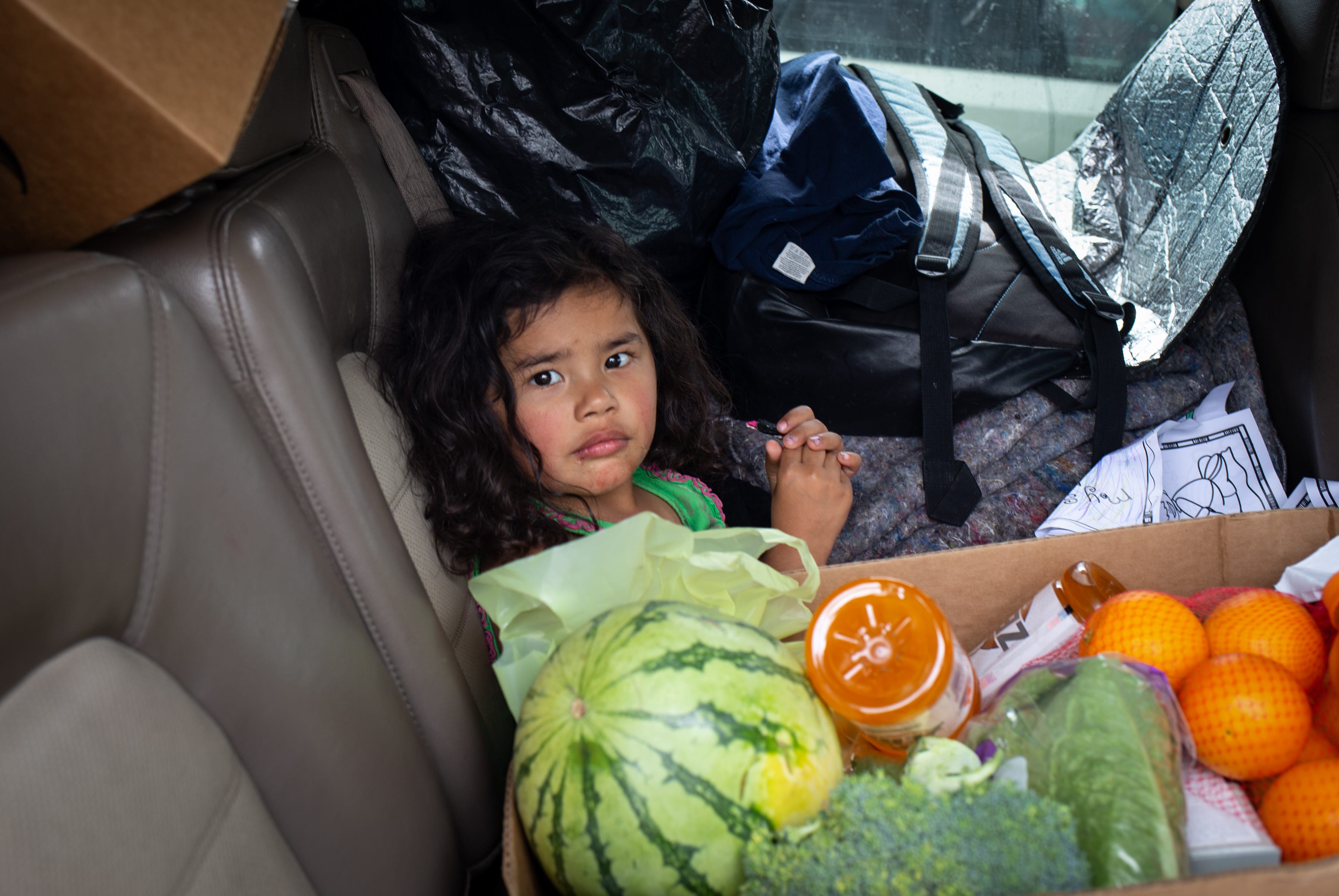 Amelia Calles, 3, sits next to a food box on March 25, 2020, at the St. Mary’s Food Bank Alliance in west Phoenix.